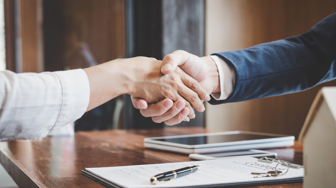 A businesswoman and a customer shaking hands after the contract signing