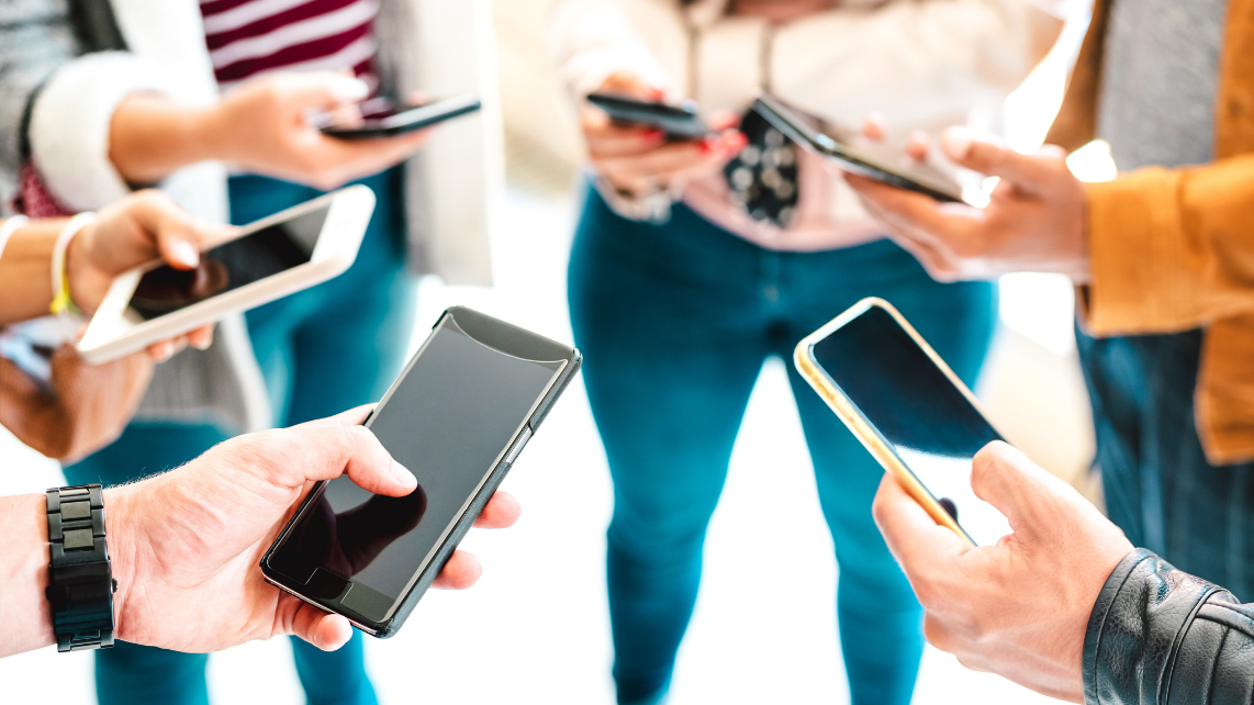 A group of friends sharing content on smartphones. Close up shot of mobile phones and hands