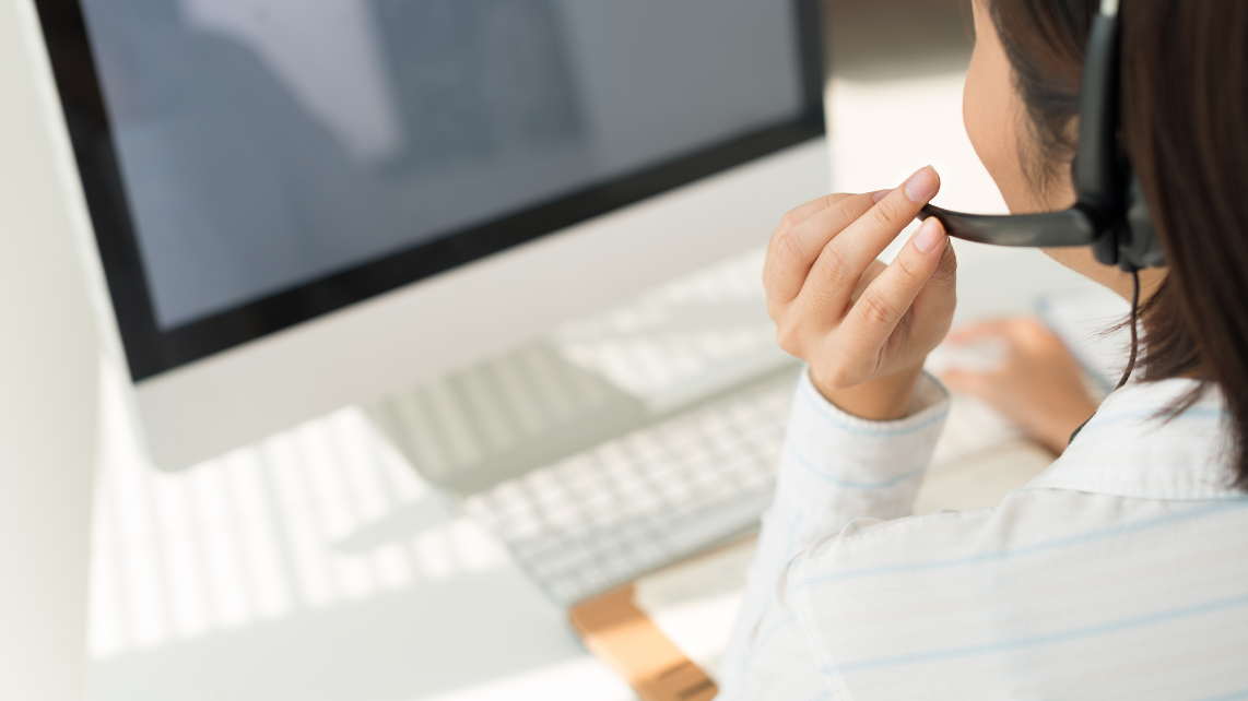 A woman with headset working on computer, view over the shoulder