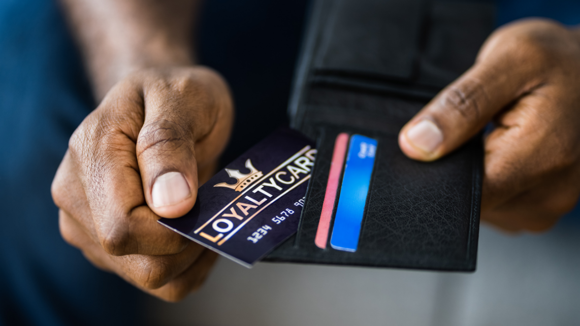 A man holding his wallet and getting his loyalty reward points program card