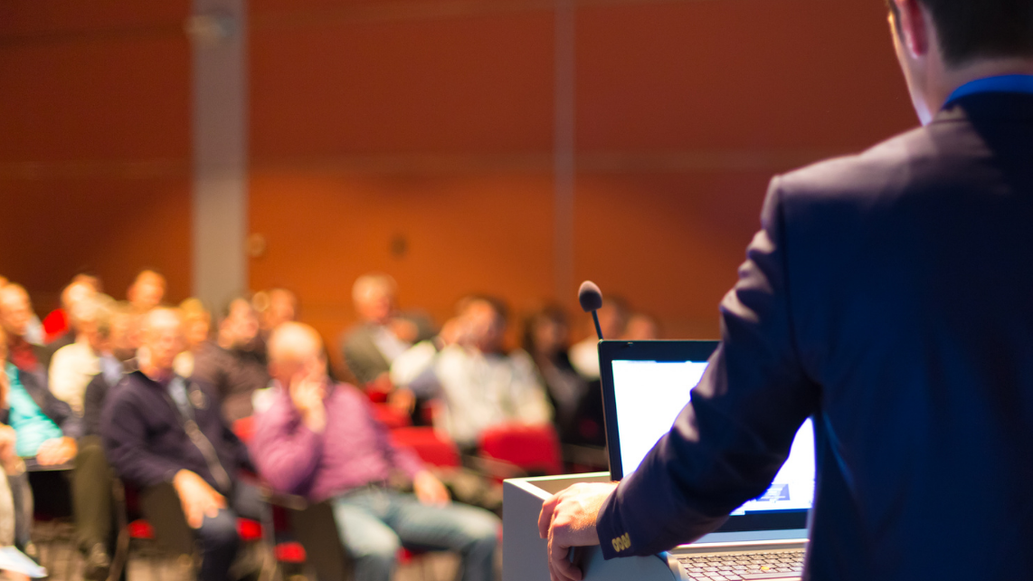 A businessman speaking on the stage during an event