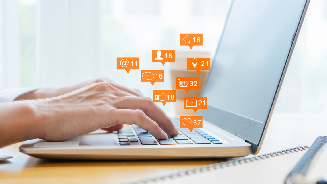 A women typing on her laptop, with communication and engagement icons floating above the keyboard