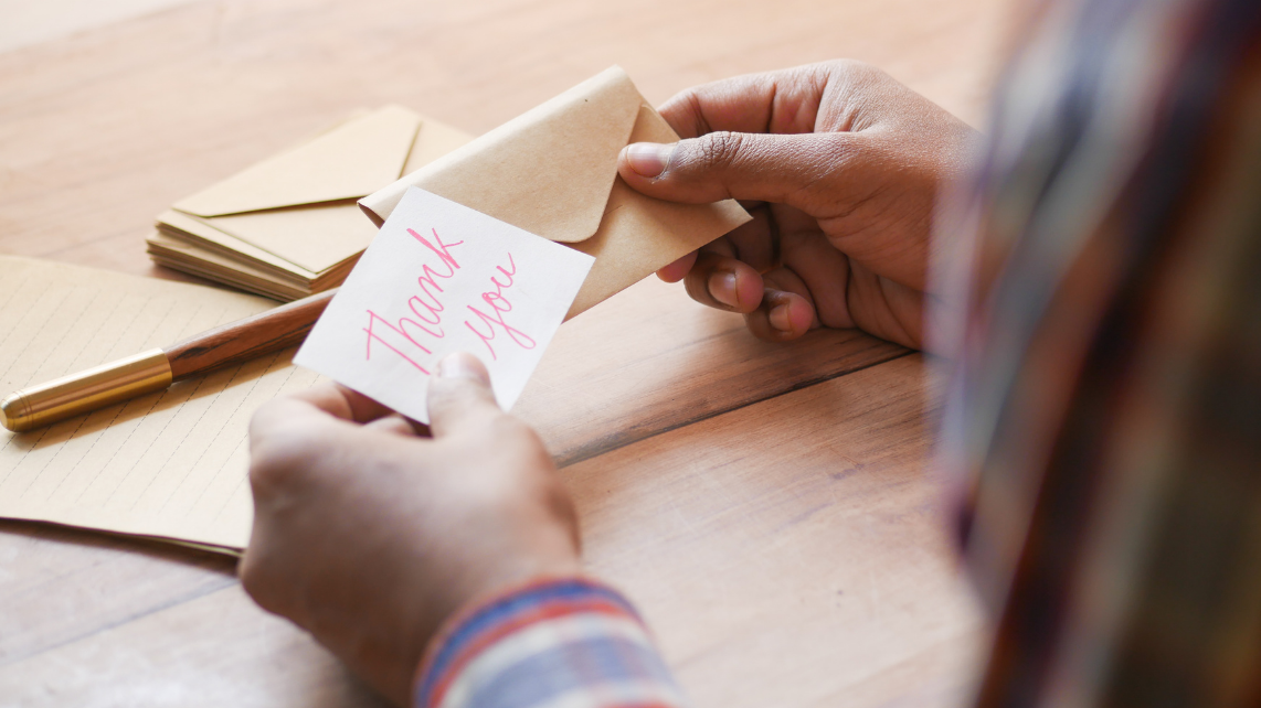 Close up of a man holding a thank you letter