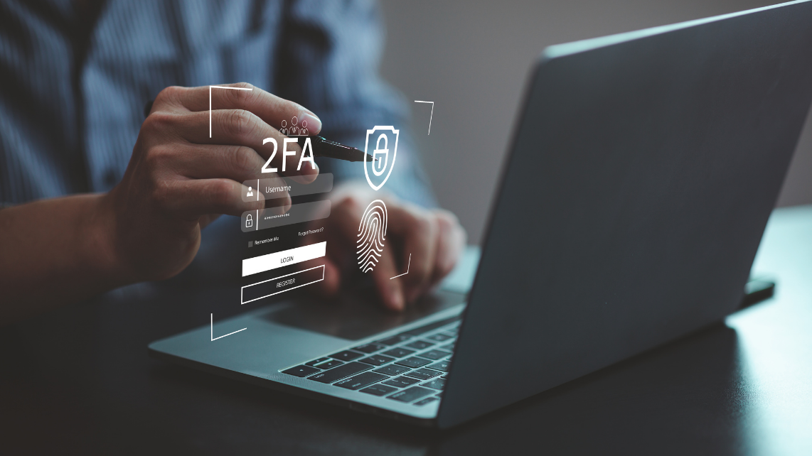 A man using a laptop with a hologram of username and password and biometrics security, representing MFA