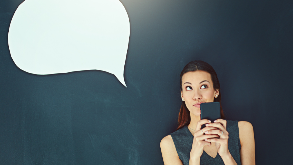 A woman thinking for a reply while holding her phone and has a thought bubble above her head