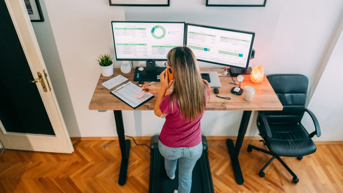 A woman working at standing desk and using her treadmill
