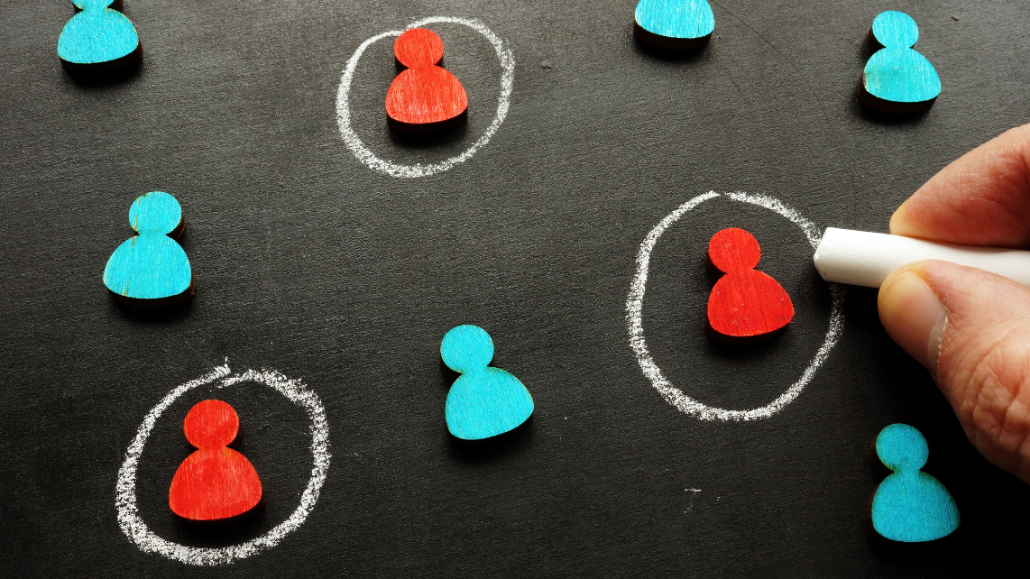 A hand with chalk encircling red human avatars but not the blue ones
