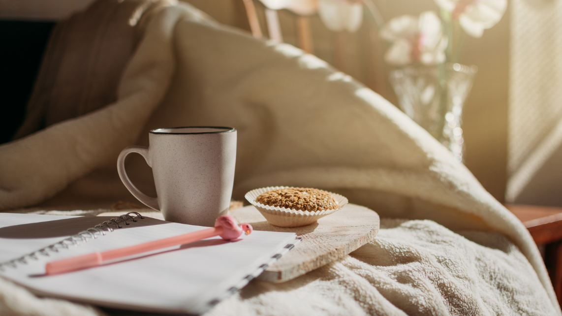 Bed with a cup of coffee, notebook, and cookie