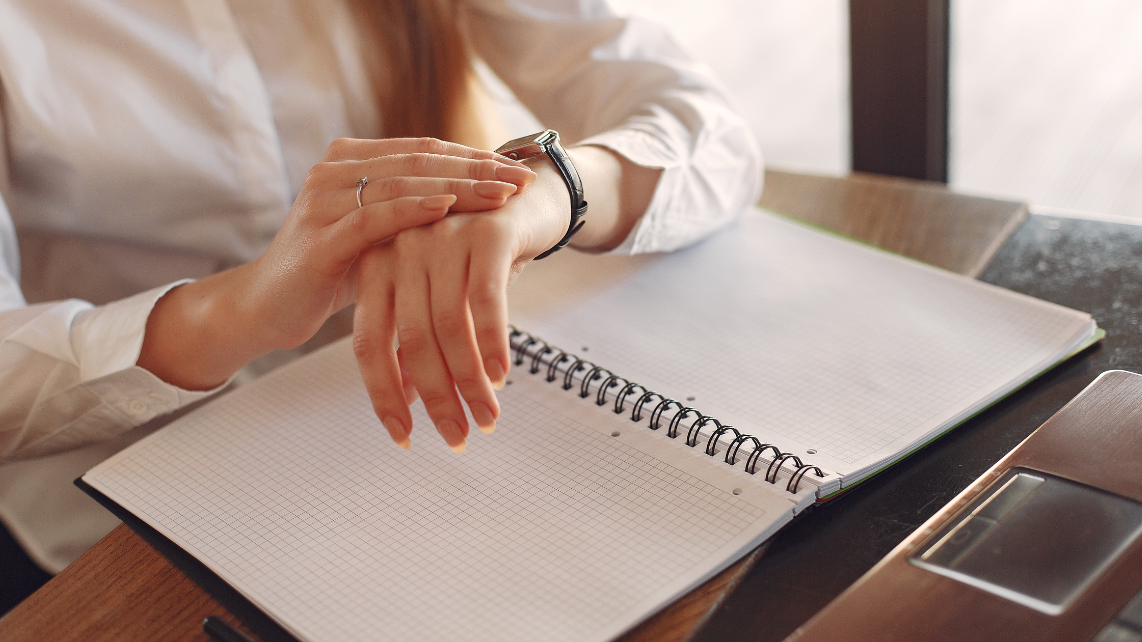 A businesswoman checking time on her watch while working on papers