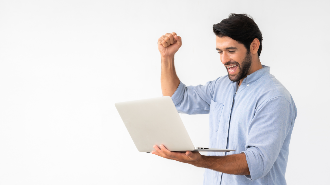 A man holding laptop while celebrating success